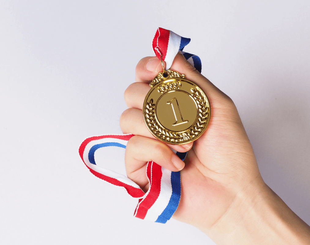 Holding a first place medal. Pacing for Success Lessons from the Olympics and Beyond